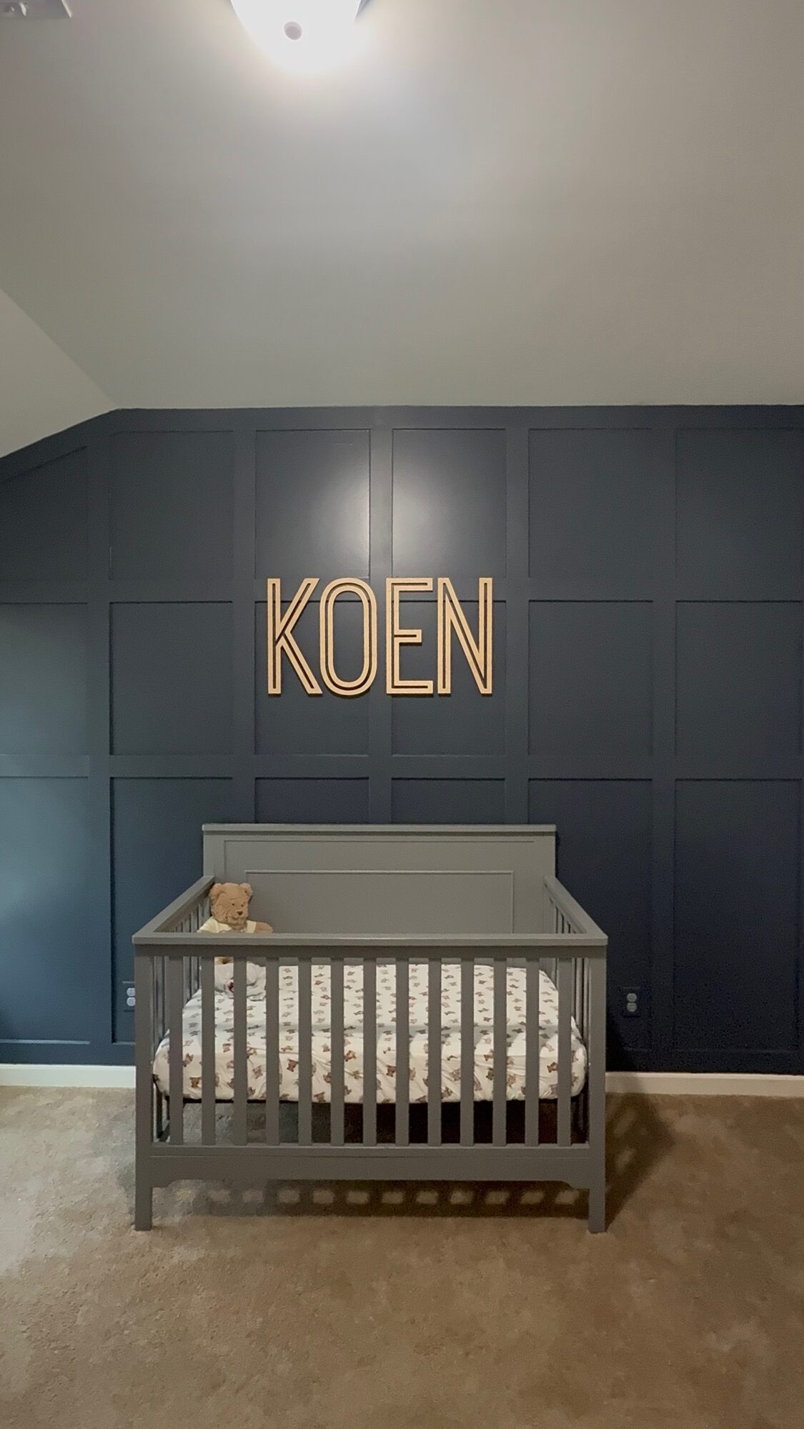 Navy board-and-batten nursery accent wall with custom name sign
