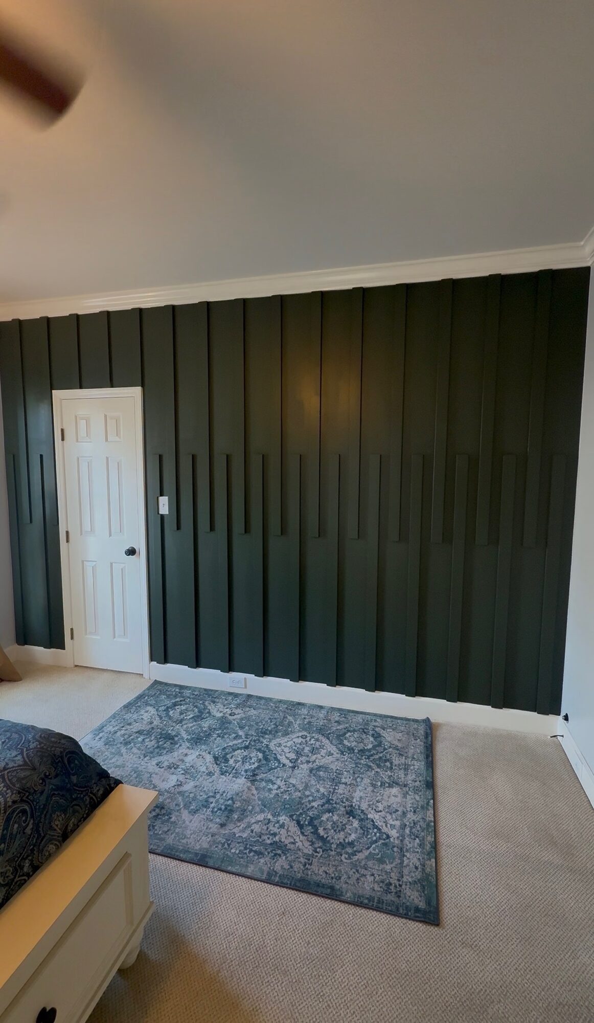 Green vertical slat accent wall in a bedroom